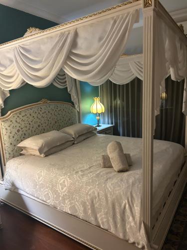 a bedroom with a white canopy bed with white curtains at Whitfords Delight Bed & Breakfast in Perth