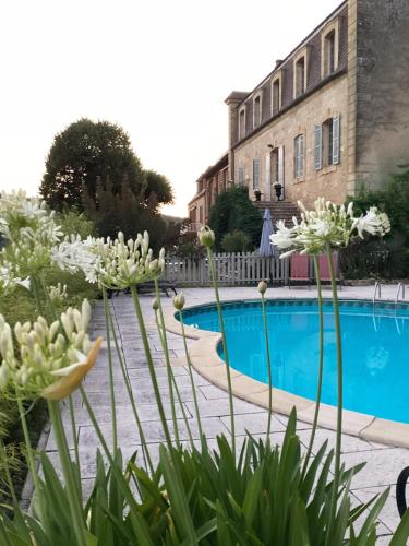 - une piscine avec des fleurs blanches en face d'un bâtiment dans l'établissement Le clos de l’Âne Dentelle, à Vézac