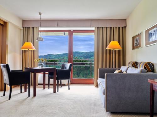 a living room with a table and a dining room at Hotel SPA Dr Irena Eris Krynica Zdrój in Krynica Zdrój