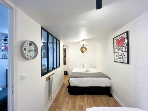 une chambre avec un lit et une horloge au mur dans l'établissement Urban Flat 150 - Pretty Flat in Center of Paris, à Paris