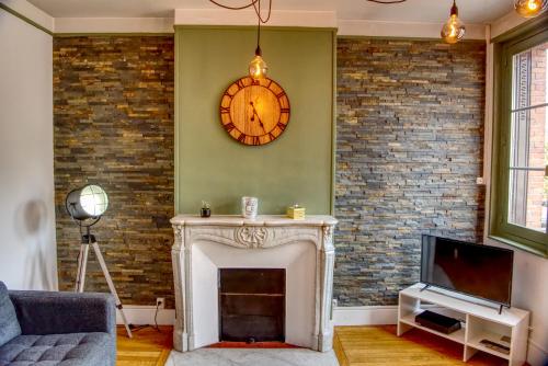 a living room with a fireplace and a clock on the wall at COSY SULLY Centre ville Château in Sully-sur-Loire
