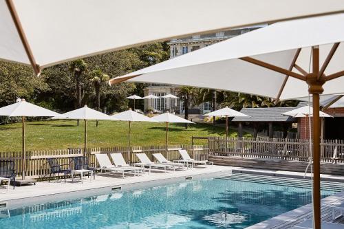 a swimming pool with white umbrellas and chairs and a pool at Villa Arthus-Bertrand in Noirmoutier-en-l'lle