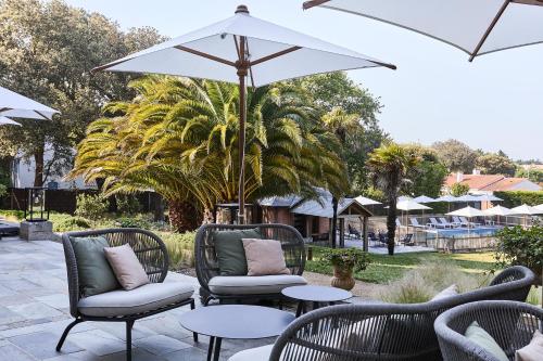 a patio with chairs and tables and an umbrella at Villa Arthus-Bertrand in Noirmoutier-en-l'lle