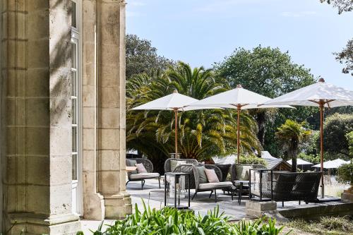 a patio with tables and chairs and umbrellas at Villa Arthus-Bertrand in Noirmoutier-en-l'lle