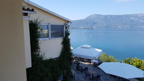 a balcony with tables and umbrellas and a view of the water at Dimitra Apartments K in Kommeno