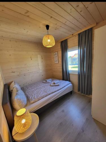 a small room with a bed in a wooden cabin at Family Resort Gąski in Gąski