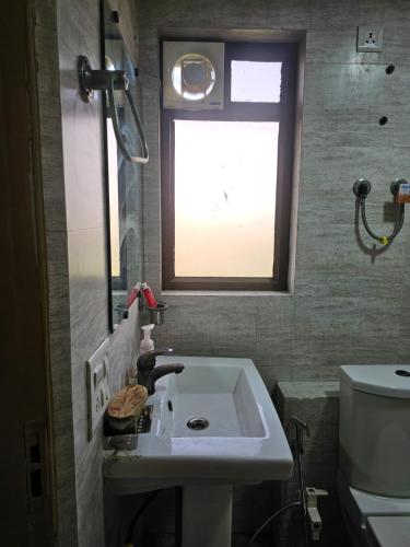a bathroom with a sink and a window at Walk to Temples in Chhatikara