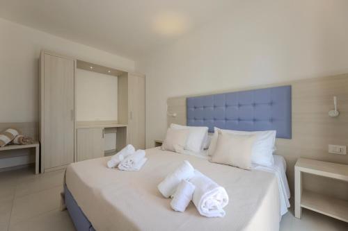 a bedroom with a large white bed with towels on it at Scirocco Boutique Eco Hotel in Torre Pali 