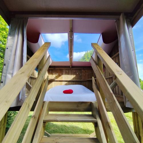 a bed in a tree house with a window at Friendly Camping and Lodges in Saint-Pardoux-la-Rivière