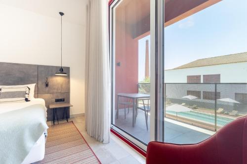 a bedroom with a bed and a balcony with a table at Hotel da Barrosinha in Alcácer do Sal