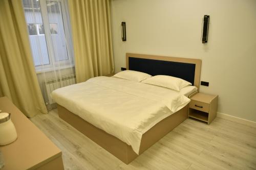 a bedroom with a large white bed and a window at QUT Hotel in Almaty