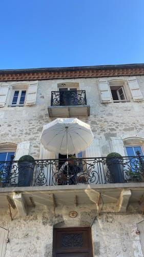 un edificio con una sombrilla en el balcón en Chambre D'hôtes Maison Avenue Mondenard, en Nérac