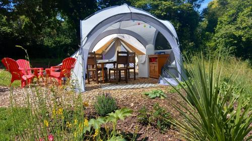 a tent with a table and chairs in a garden at Tente insolite en pleine nature in Tréduder