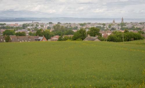 a field of green grass with a city in the background at Pipeland Farm Steading - No 4 in St. Andrews