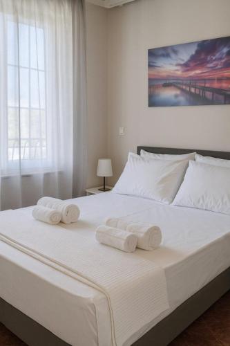a bedroom with a large white bed with towels on it at Bright & comfortable apartment for a pleasant stay! in Vari