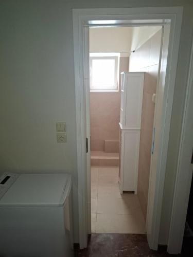 a small bathroom with a white refrigerator and a window at Bright & comfortable apartment for a pleasant stay! in Vari