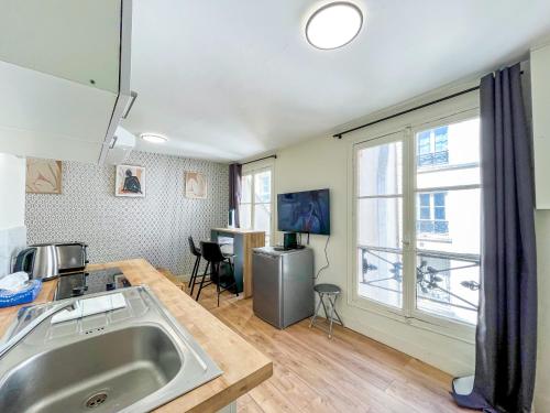 une cuisine avec un évier et une grande fenêtre dans l'établissement 163 - Urban Studio in Paris, à Paris