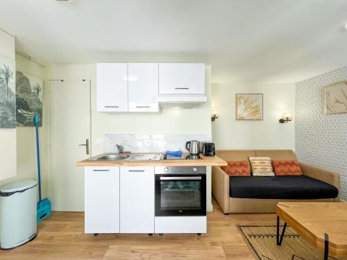 une cuisine avec des armoires blanches et un canapé dans une pièce dans l'établissement 163 - Urban Studio in Paris, à Paris