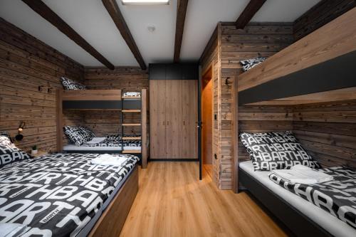 two beds in a room with wooden walls at Wellness apartmány BARTH Holiday in Dolní Morava