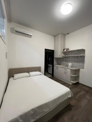 a bedroom with a large white bed and a kitchen at Royal Suite in Odesa