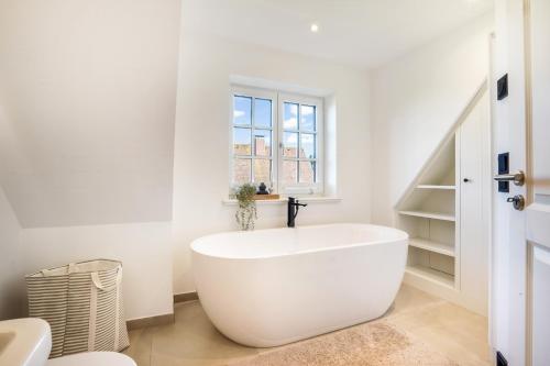 une baignoire blanche dans une salle de bains avec fenêtre dans l'établissement Sky & Sand, à Westerland