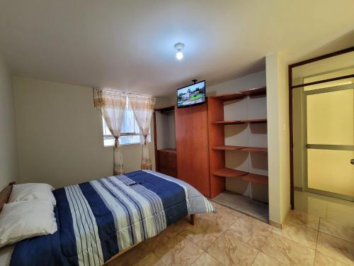 a bedroom with a bed and a tv on the wall at Tu Espacio Exclusivo Privacidad y Comodidad in Tacna
