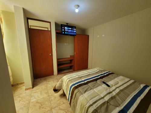 a bedroom with a bed and a tv on the wall at Tu Espacio Exclusivo Privacidad y Comodidad in Tacna