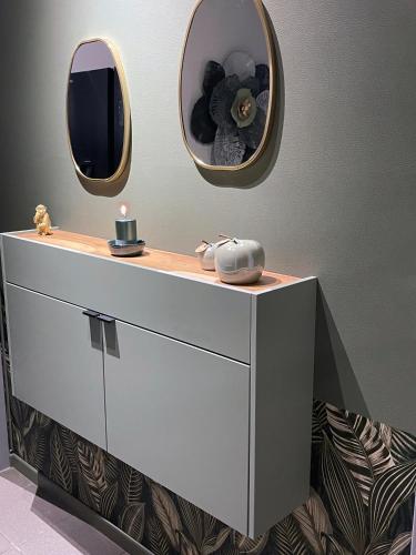a white dresser with two mirrors on top of it at Metropolitan am Schloßpark in Paderborn