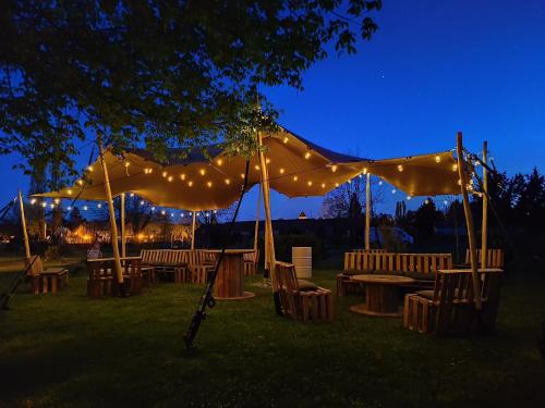 a tent with tables and chairs under it at night at Friendly Camping and Lodges in Saint-Pardoux-la-Rivière