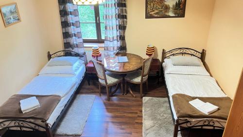 two beds in a room with a table and chairs at Penzion Kersko in Hradišťko