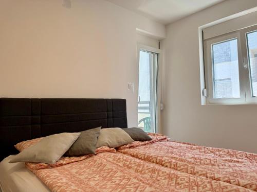 a bedroom with a bed with a orange comforter and two windows at Mirabela Apartman Sokobanja in Soko Banja