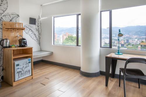 a room with a desk and a table and windows at Socialtel Medellin in Medellín