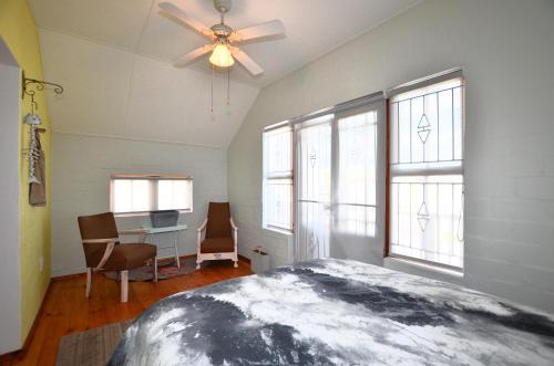 a bedroom with a ceiling fan and a desk with chairs at Paradise Nook in Yzerfontein