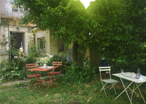 a table and chairs sitting under a tree at Une chambre au jardin in Saint-Pons-de-Thomières