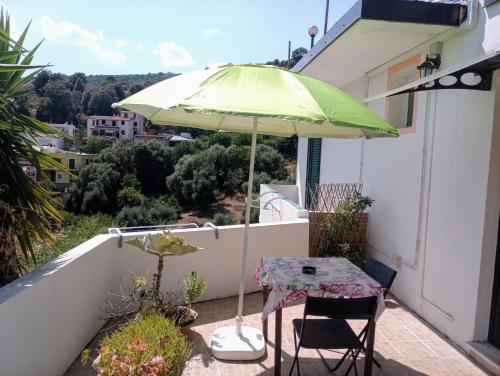 a table with a green umbrella on a balcony at Locanda D'Ogliastra, in Triei