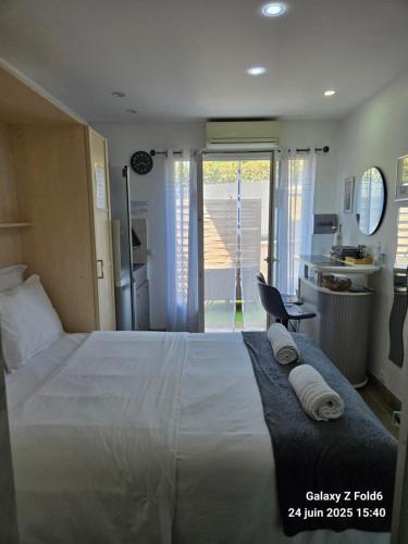 une chambre avec un grand lit blanc avec des serviettes dessus dans l'établissement 2 Chambres paisibles à La Trinité proche de Nice 15 mn, Monaco 20 mn et l'Italie 30 mn et aussi 2 Studios dans le même établissement, à La Trinité