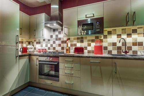 a kitchen with white cabinets and a microwave at Silversprings - City Centre Apartments with Parking in Exeter
