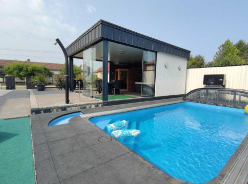 a swimming pool in front of a house at Theresa Vendégház in Kiskunmajsa