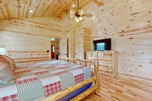 a log cabin bedroom with a bed and a tv at Southern Comfort Cabin By Avada Properties in Gatlinburg