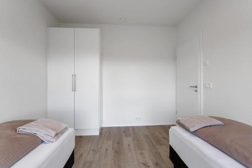 two beds in a room with white walls and wooden floors at 3BR Modern & Spacious Golden Circle Home in Reykholt