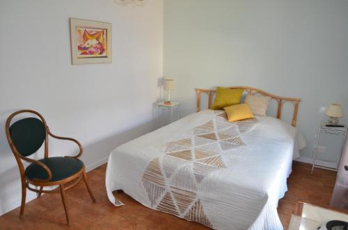 una camera da letto con un letto bianco e una sedia di Chambre Pantagruel Le dolmen a Thizay