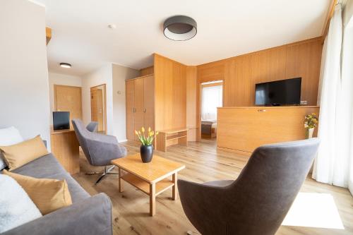 a living room with a couch and chairs and a tv at Passerblick in Tirolo