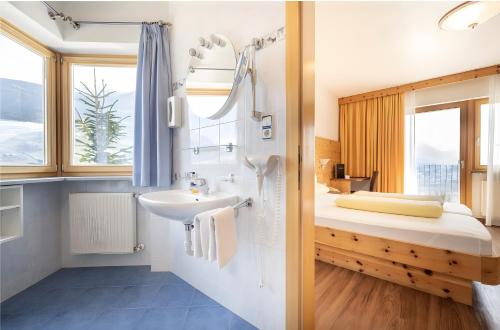 a bathroom with a sink and a bed with a window at Passerblick in Tirolo