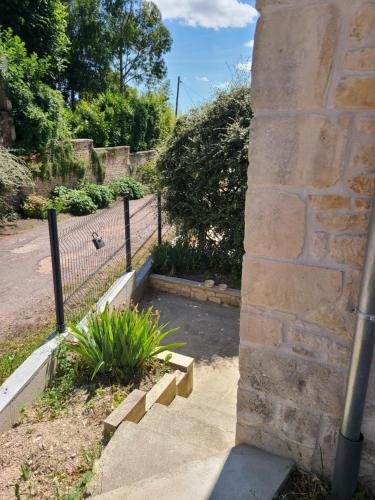 a stone retaining wall with a gate and a plant at Maison en pierre de Caen charmante et confortable et sa terrasse privative entre terre et mer in Bretteville-sur-Odon