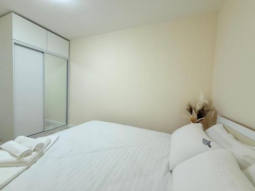 a white bedroom with a bed with white sheets and pillows at Modern 2BR Next to Dept Store in Ulaanbaatar