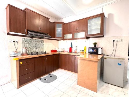 a kitchen with wooden cabinets and a refrigerator at Cozy Murni 14th Entire 3 Bedroom House at Alma Bkt Mertajam in Bukit Mertajam
