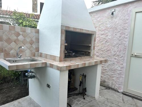 een buitenkeuken met een wastafel en een open haard bij Casa Ginepro in Olbia