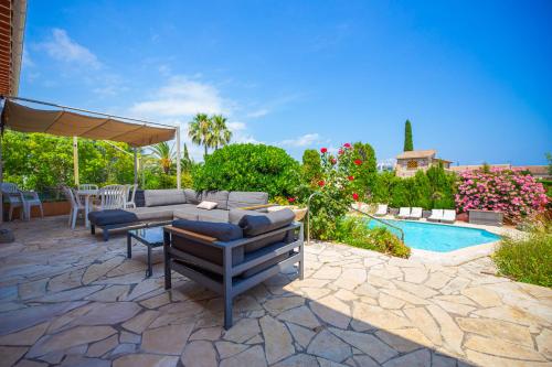 un patio avec une table et des chaises à côté d'une piscine dans l'établissement Mas Des Lavandes, à Mandelieu-la-Napoule