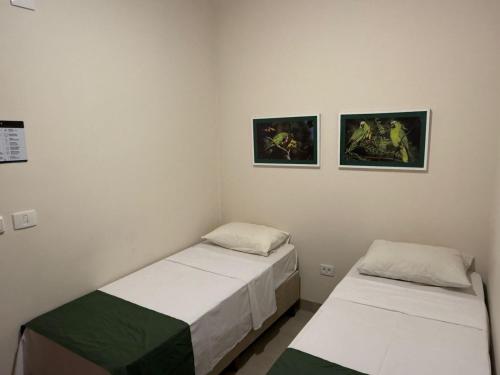 two beds in a room with two pictures on the wall at Hotel Santa Catarina in Três Lagoas