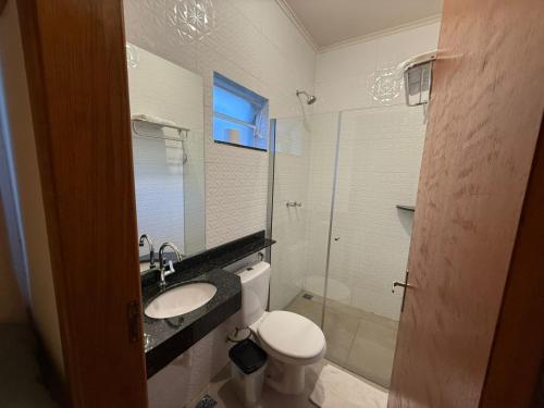 a bathroom with a toilet and a sink and a mirror at Hotel Santa Catarina in Três Lagoas